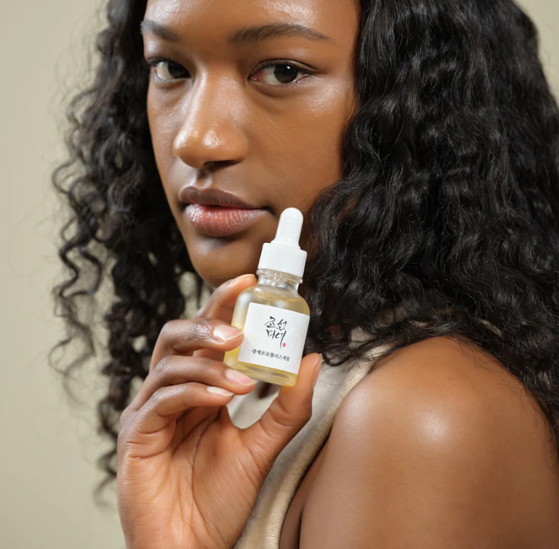 Woman holding a skincare dropper bottle with a beige background