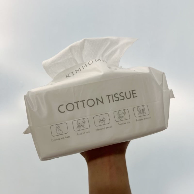 Package of Kimhome cotton tissue held by a hand against a light gray background