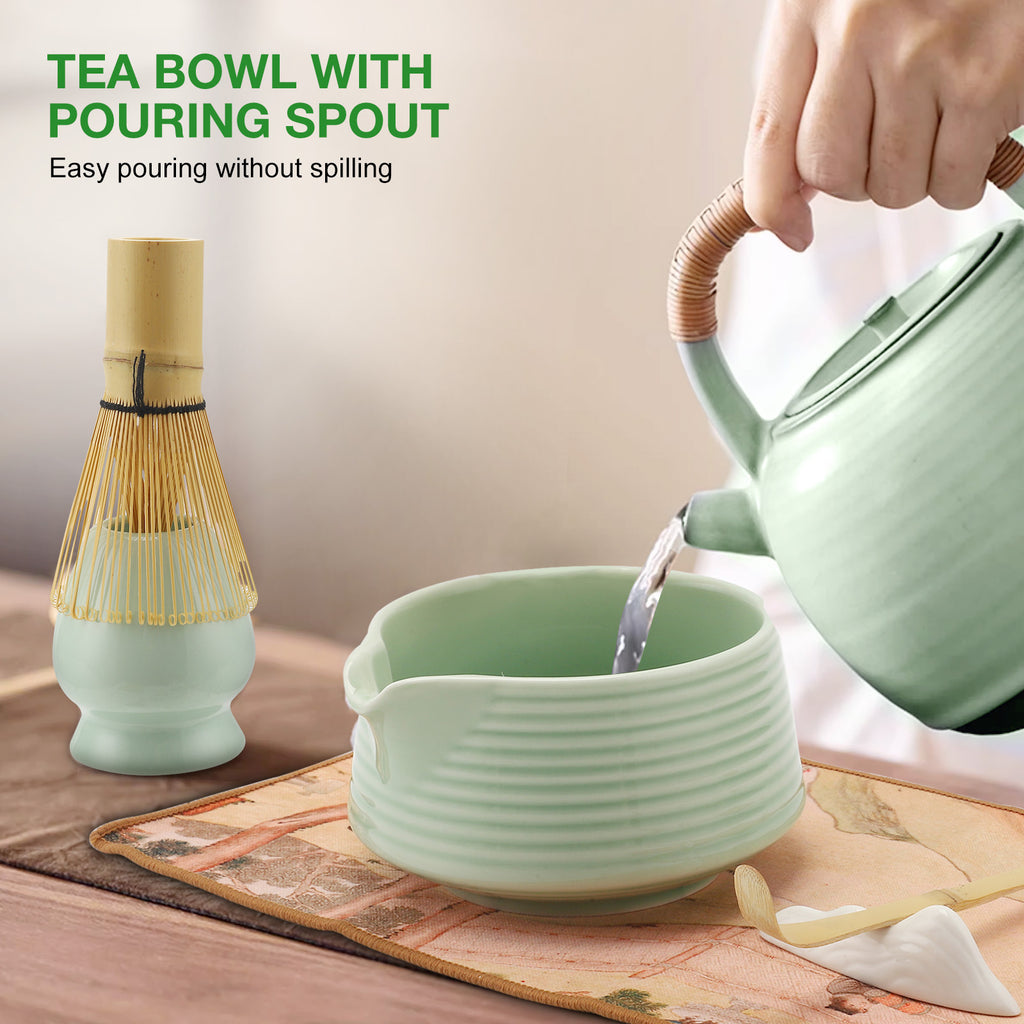 Tea bowl with pouring spout being filled by a teapot on a wooden surface.
