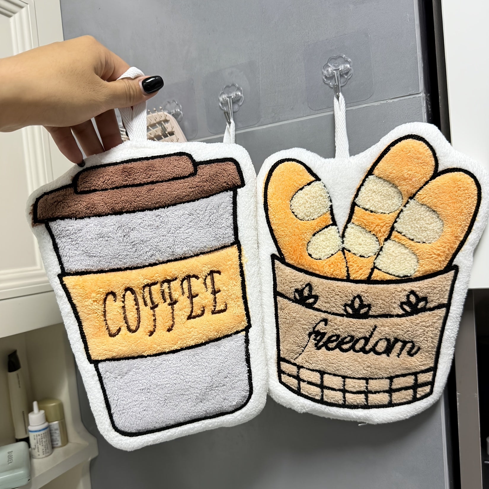 Two plush items shaped like a coffee cup and a basket with bread, hanging on hooks.
