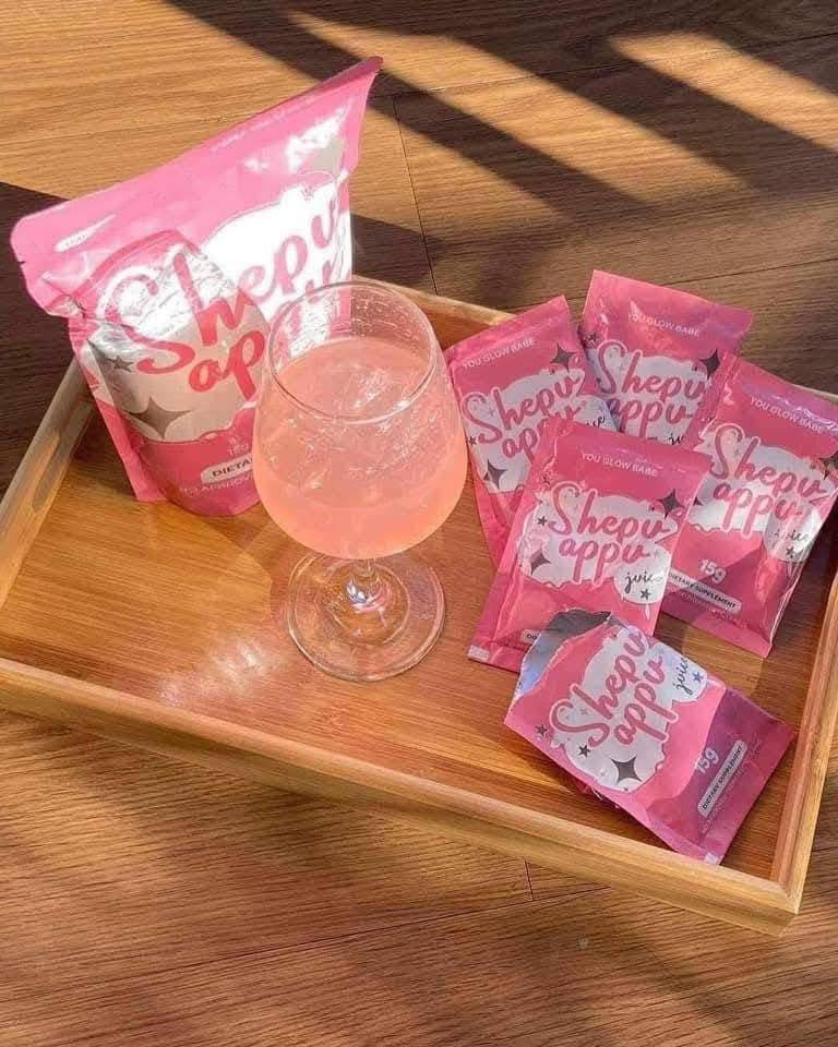 You glow babe sachets in a tray and a wine glass of juice in wooden floor background