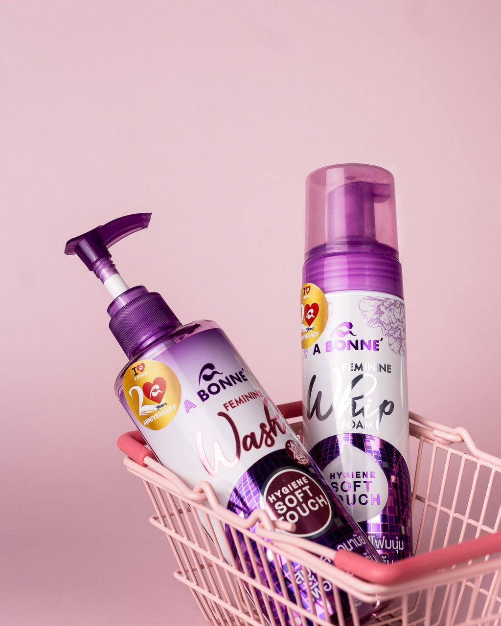 Two bottles of A Bonne hygiene products in a pink basket against a light pink background