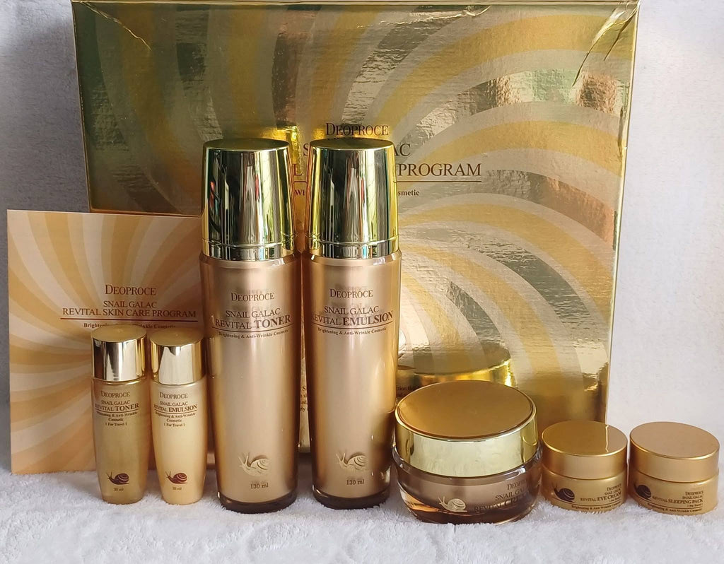 Cosmetic set with gold and bronze bottles and containers in front of a decorative box.