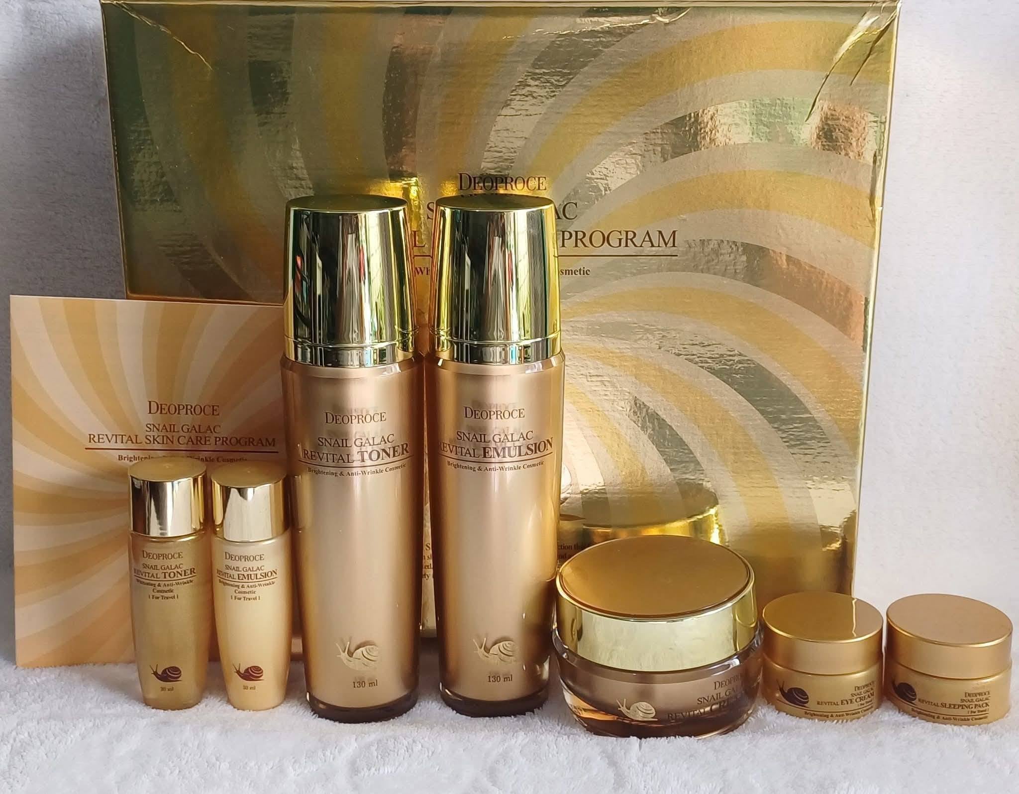 Cosmetic set with gold and bronze bottles and containers in front of a decorative box.