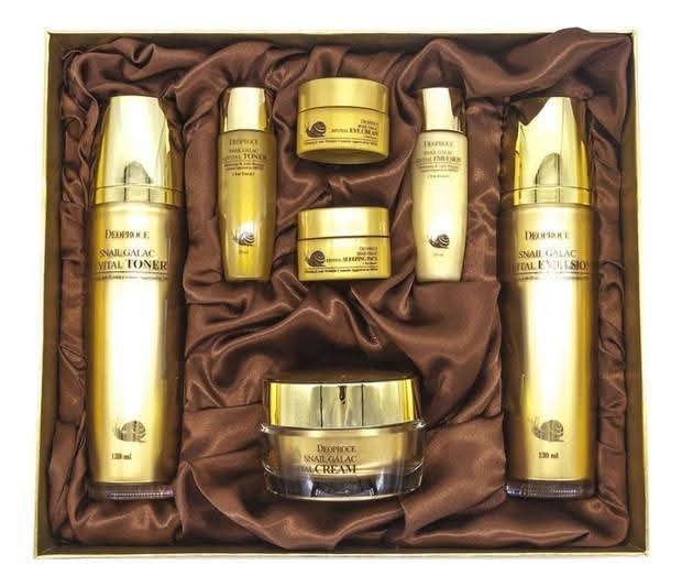 Set of gold and brown skincare products in a box with brown satin lining.