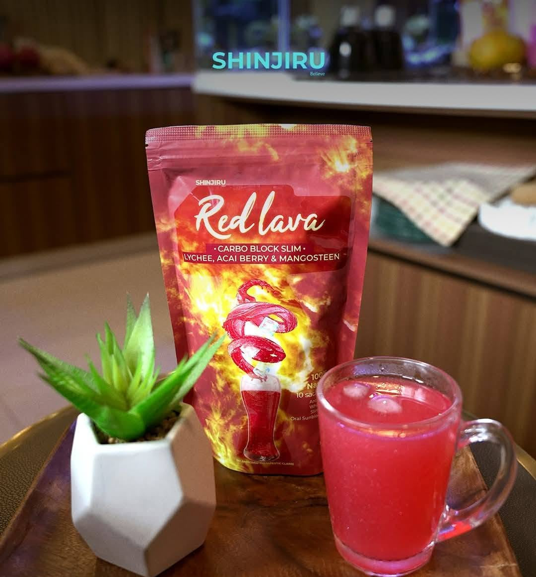 A pouch of Shinjiru Red Lava carbo block slim with a glass of pink drink and a small potted plant on a wooden tray in a kitchen setting.