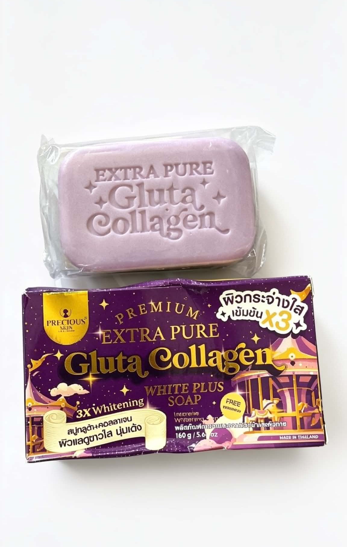 A bar of lavender-colored gluta collagen soap wrapped in clear plastic, placed above its purple and gold retail packaging box on a plain white background.