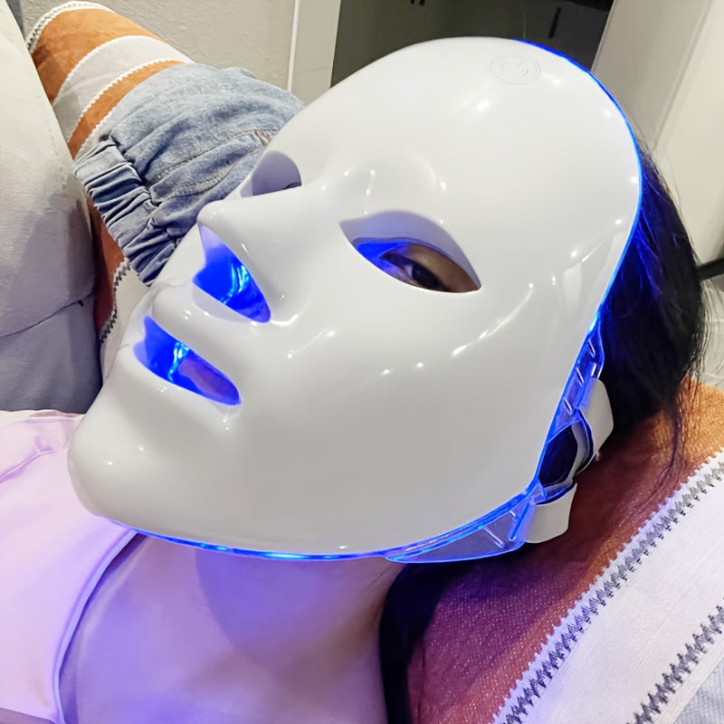 Person wearing a white LED face mask with blue light on a couch.