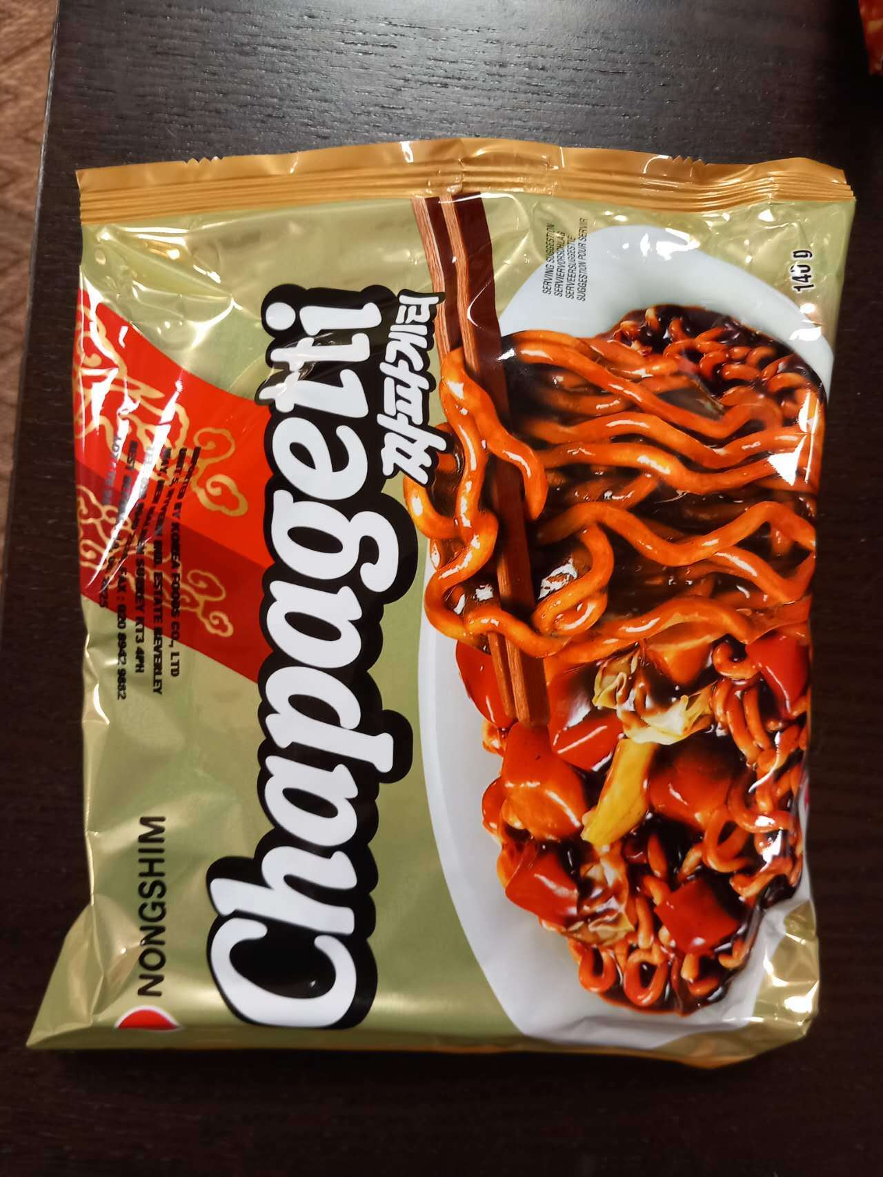 Packaged snack with noodles and sauce on a dark surface