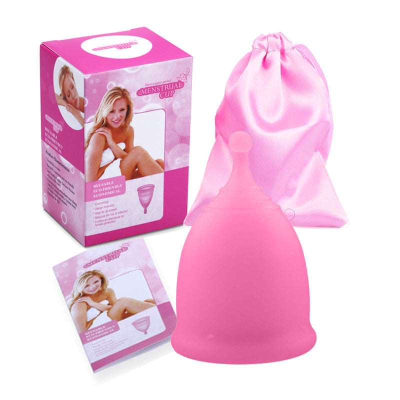 Pink menstrual cup with packaging, box, and drawstring bag on a white background