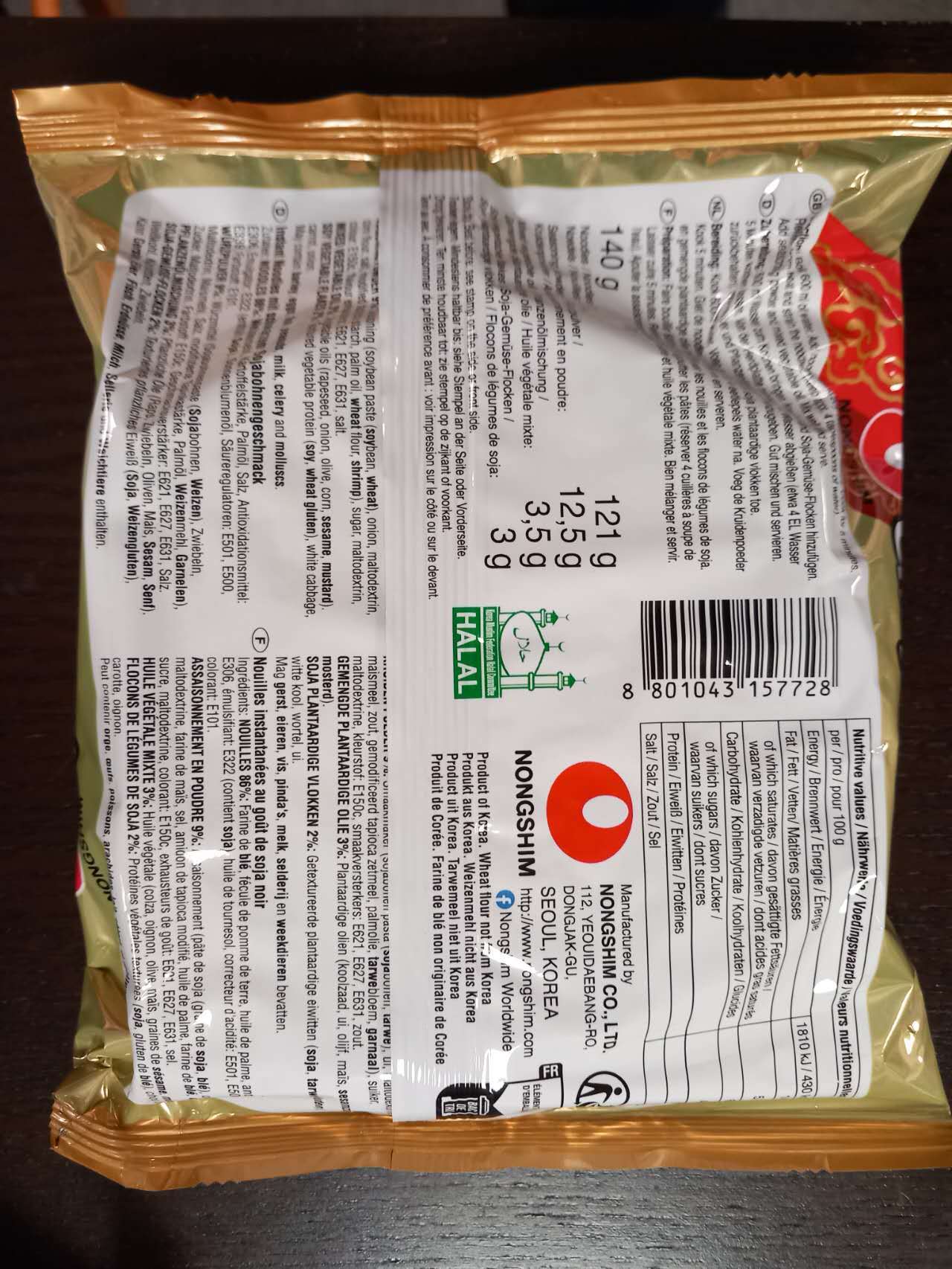 Back view of a food packaging with text and a barcode on a dark surface