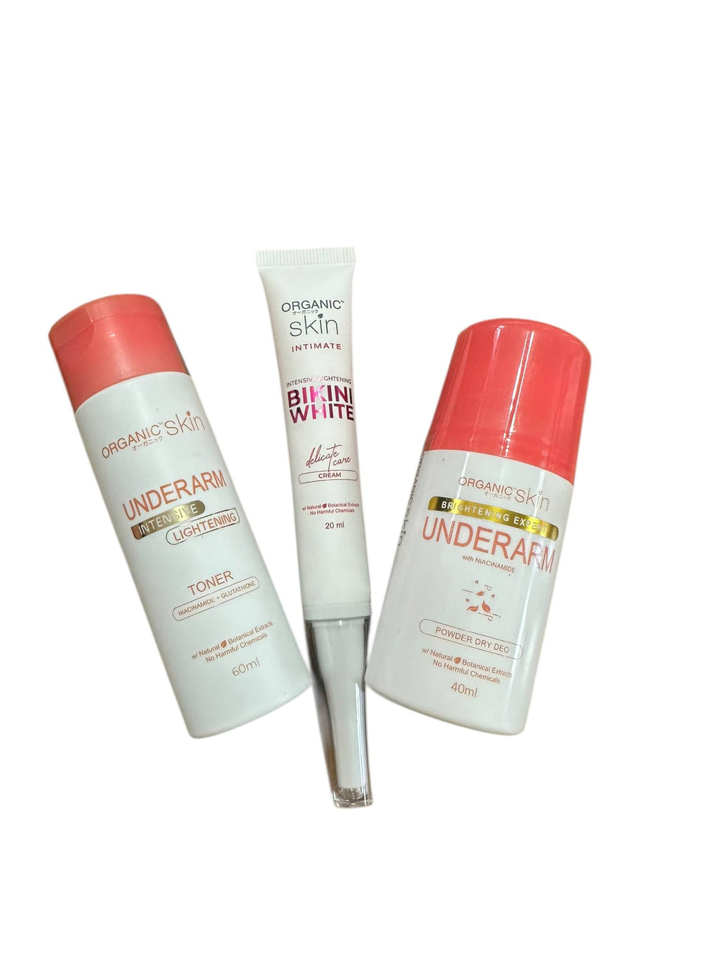 Three bottles of skincare products with coral and white packaging on a white background.