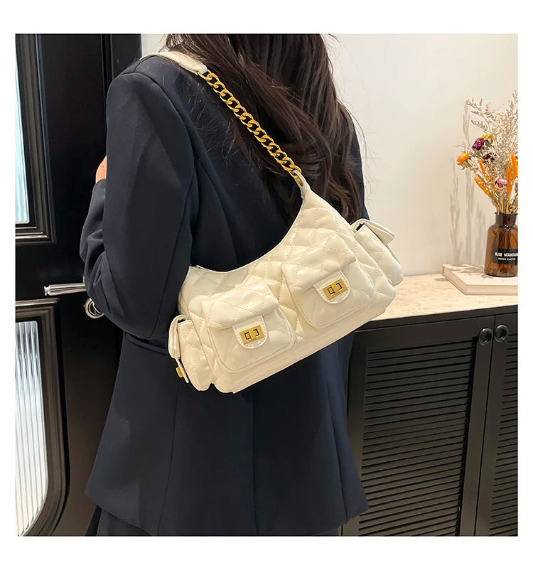 Person wearing a white quilted handbag with gold chain strap indoors.
