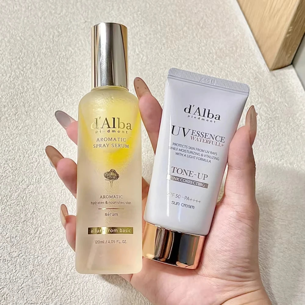 Hand holding d'Alba skincare products against a neutral background