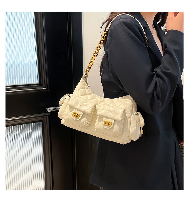Person wearing a quilted beige handbag with gold chain strap indoors.