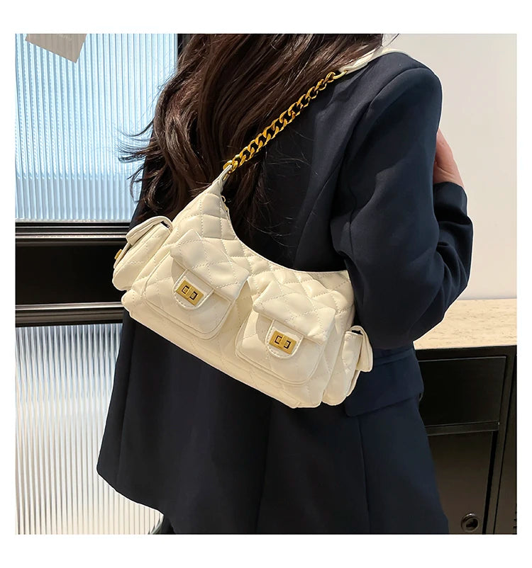 Person wearing a white quilted handbag with gold chain strap indoors.