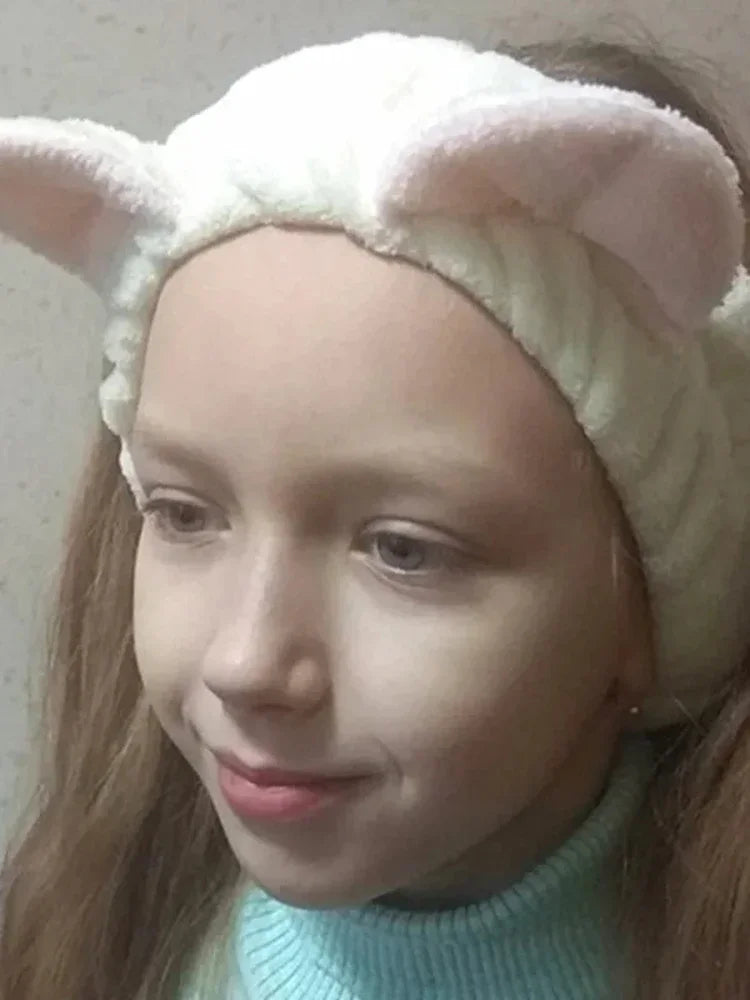 Person wearing a headband with cat ears and a light blue sweater.