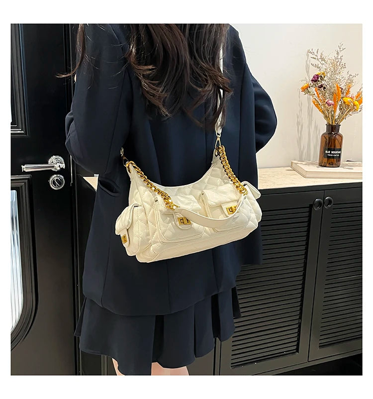 Person wearing a dark outfit with a white quilted handbag in an indoor setting.