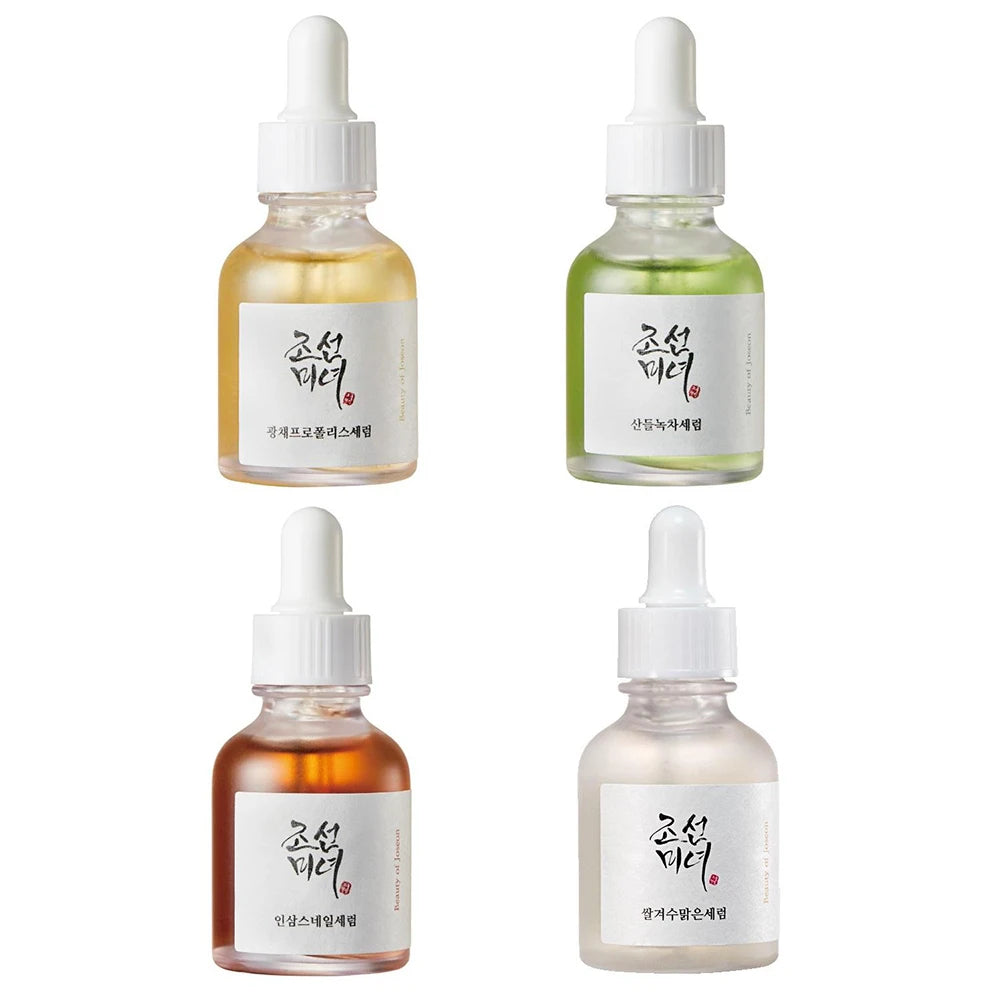 Four bottles of skincare serum with droppers on a white background
