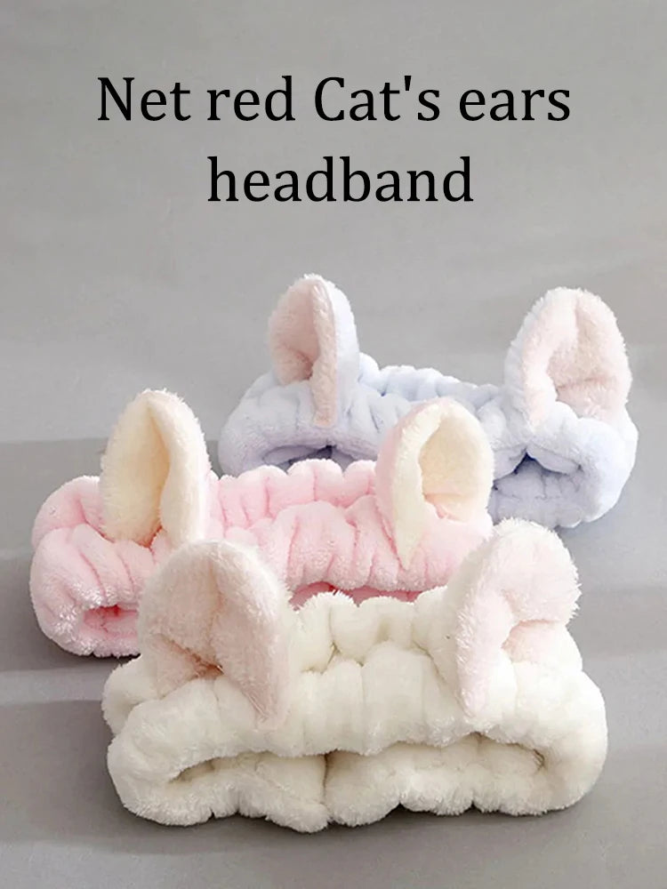 Three headbands with cat ears in pink, white, and gray on a gray background.