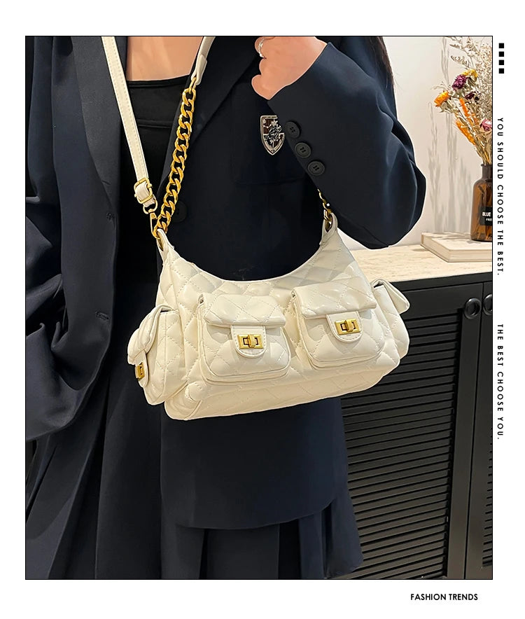 Person wearing a white quilted handbag with gold accents, standing indoors.