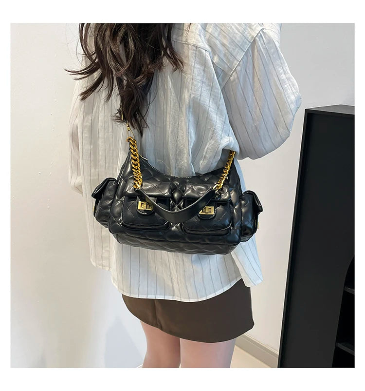 Person wearing a black handbag with gold chain strap against a neutral background
