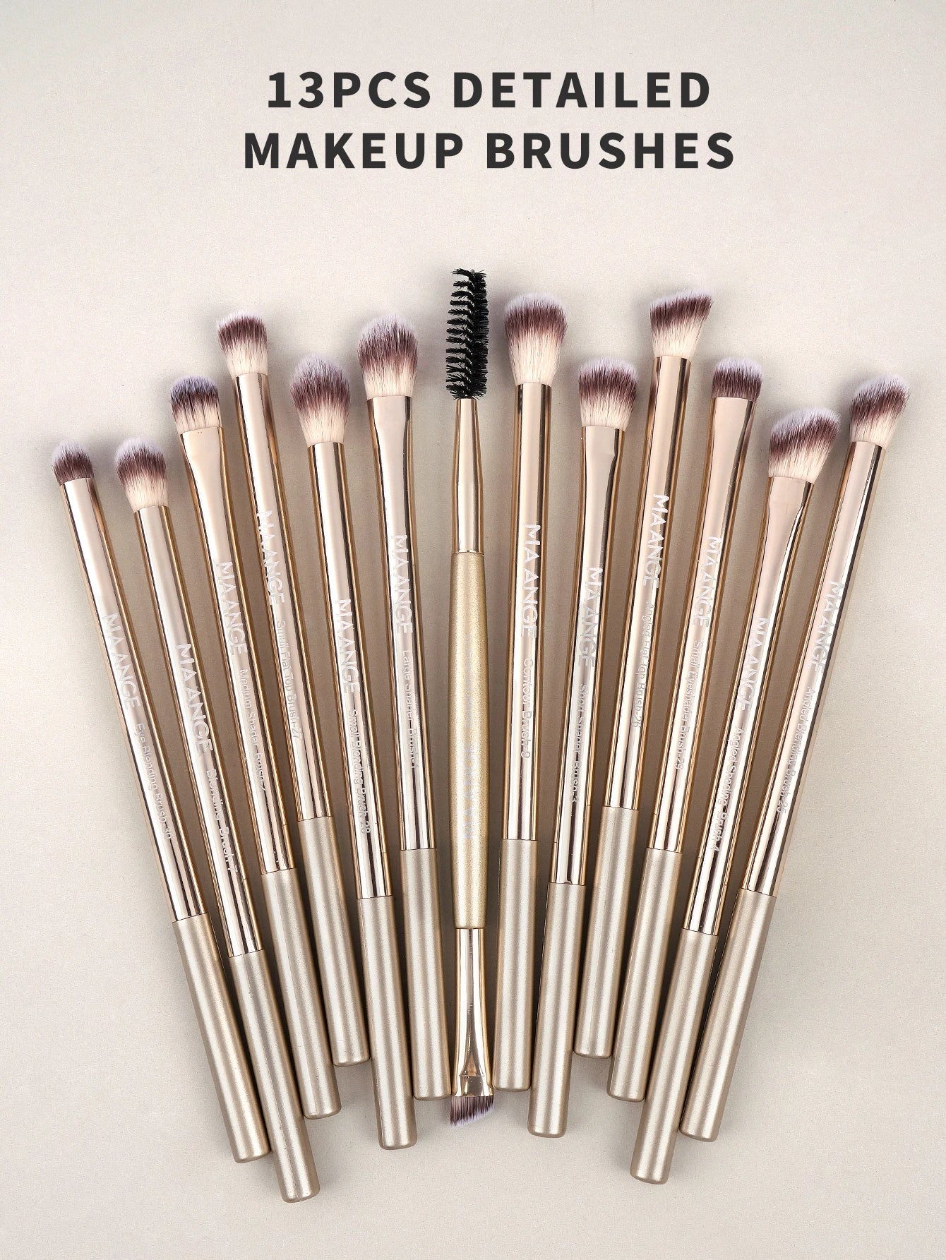 Set of 13 makeup brushes with gold handles on a light background