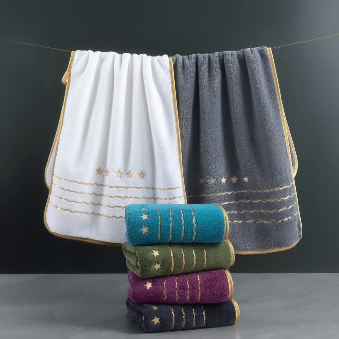 Stack of folded towels with embroidered designs on a dark background